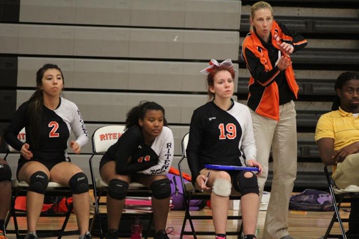 JV Volleyball player junior Courtney Harris (center) watches a match against McCluer North from the varsity bench. Harris plays both JV and Varsity games. Seniors Selena Murrilo (2) and Madison Brand (19) also watch, as Coaches Ellen Kim and Michael Loyd guide their team.