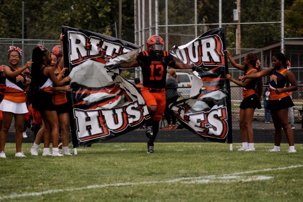 Number thirteen Billy Hall breaking through the Ritenour banner before the homecoming game.