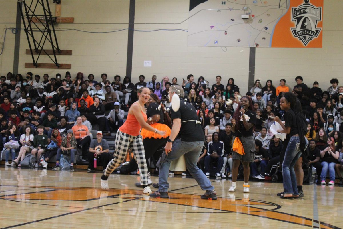 Freshman Audrey Brown throws a pie in the face of Principal Greg Jones  at the Homecoming assembly. Jones was pied as an incentive for raising money for the school's Make A Wish child.