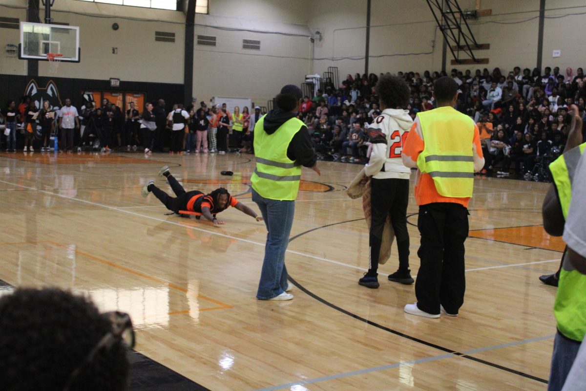 Senior Fate Finley glides across the floor on a scooter as part of a relay race at the Homecoming assembly. 
