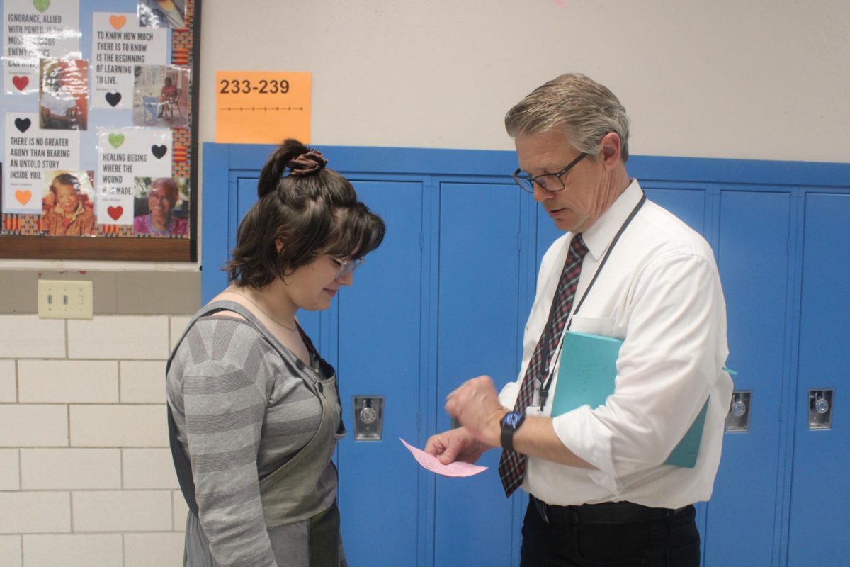 Ritenour administrator Greg Jones checks junior Mignonette Cygne's paper hall pass. Next semester the pass system will go completely digital. 